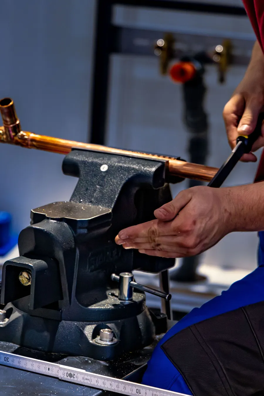Plumber bending copper pipe with a pipe bender in the workshop